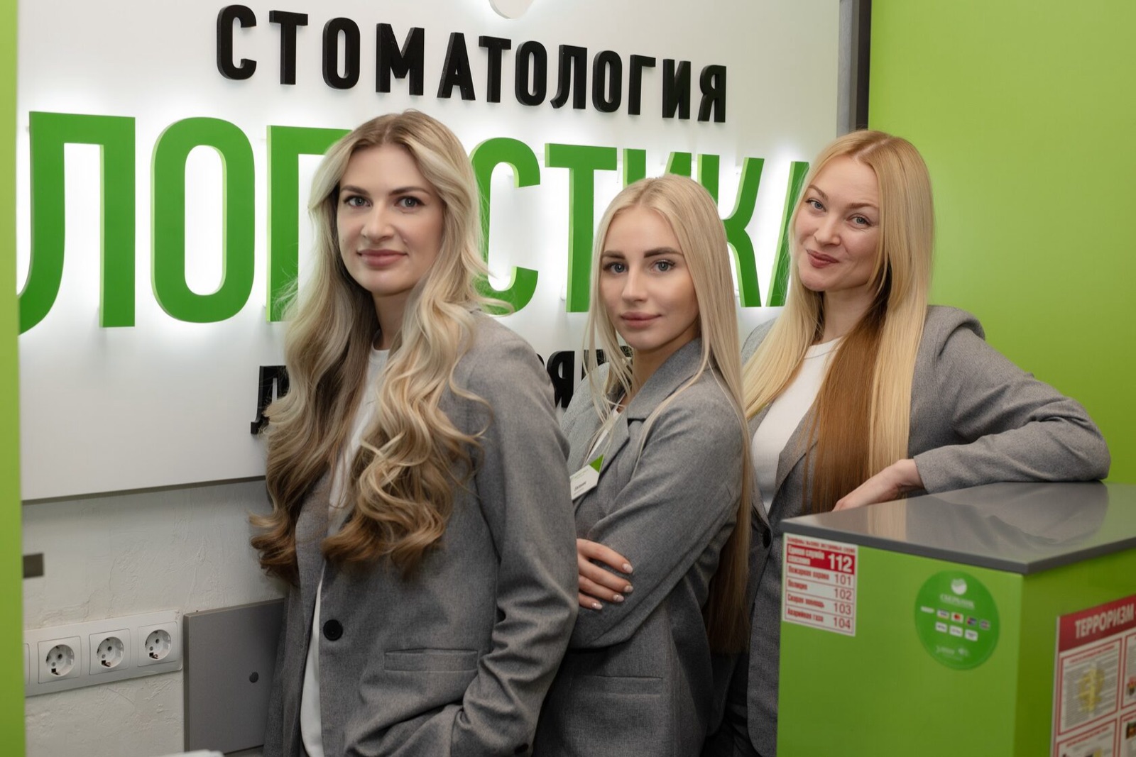 Администраторы клиники «Логистика» на ресепшене у вывески клиники